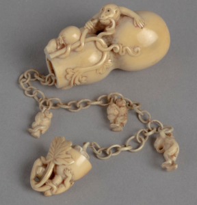 Ivory netsuke carving in the form of a double gourd opened to reveal an ivory chain with clinging monkeys.
