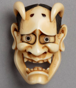 Ivory netsuke carving in the form of a theatre mask depicting a demonic woman with horns.