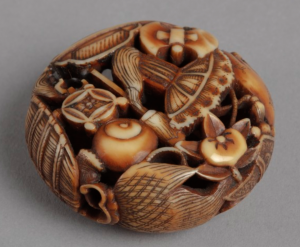Flattened circular ivory netsuke carving comprised of lucky symbols.