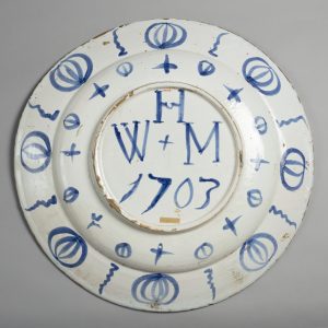 The back of a delftware plate with the initials W H M/1703